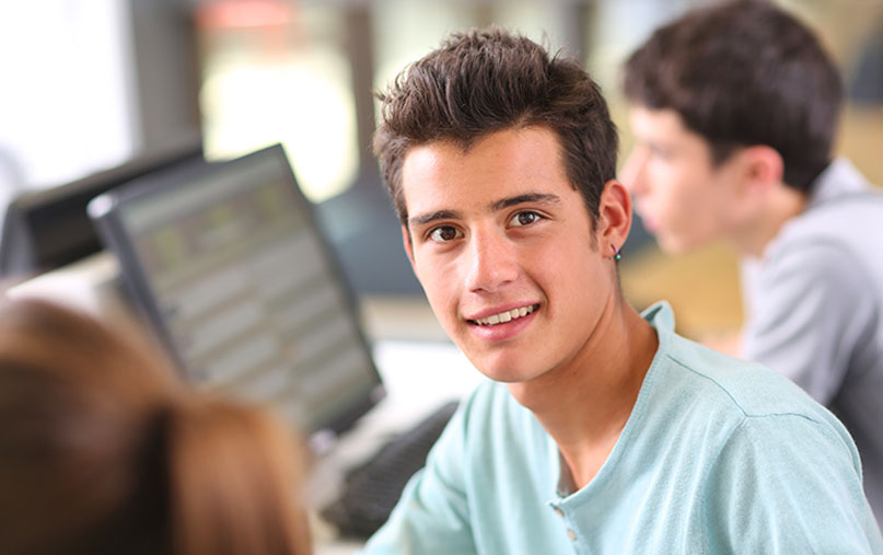 adolescente mirando a cámara en un aula con ordenadores
