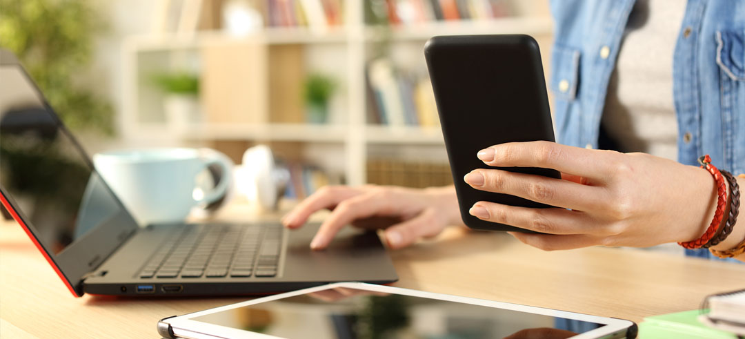 Persona utilizando un smartphone y un ordenador a la vez