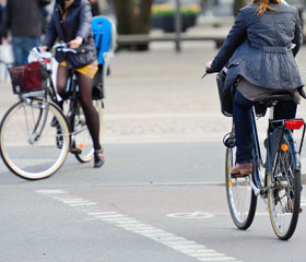 Dos personas en bicicleta cruzando un paso de peatones por el carril bici