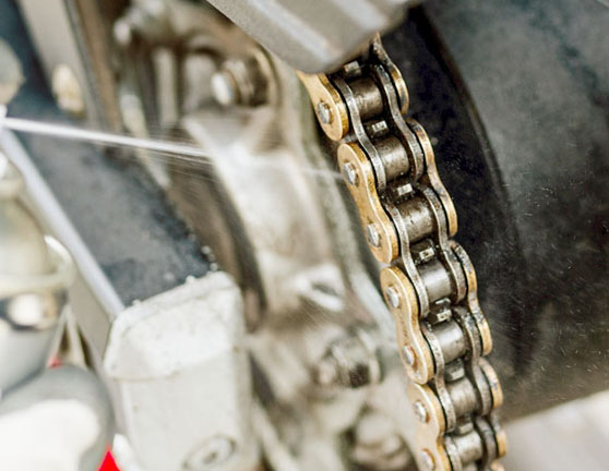 Persona engrasando la cadena de una motocicleta